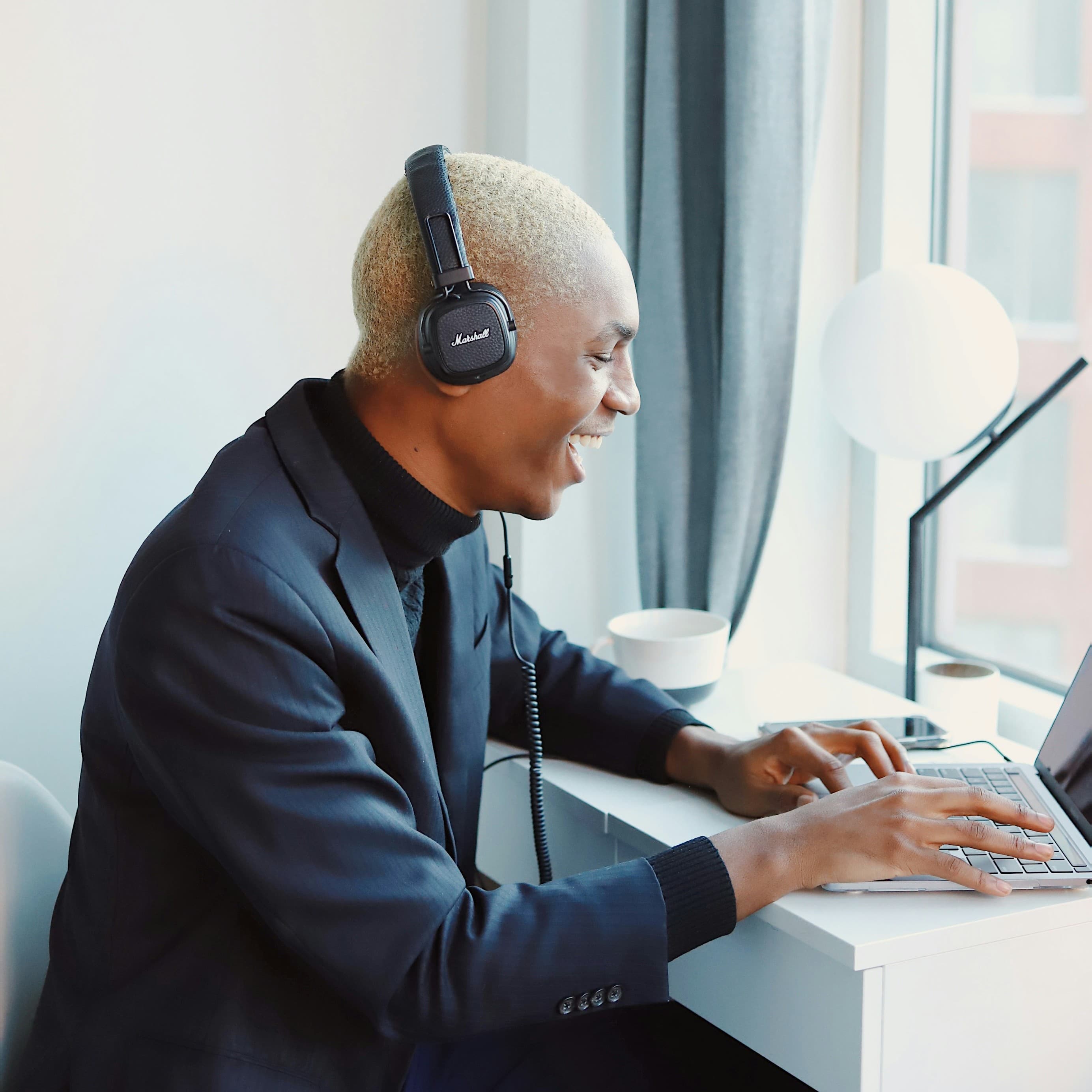 Man wearing headphones while working on a laptop during a remote call